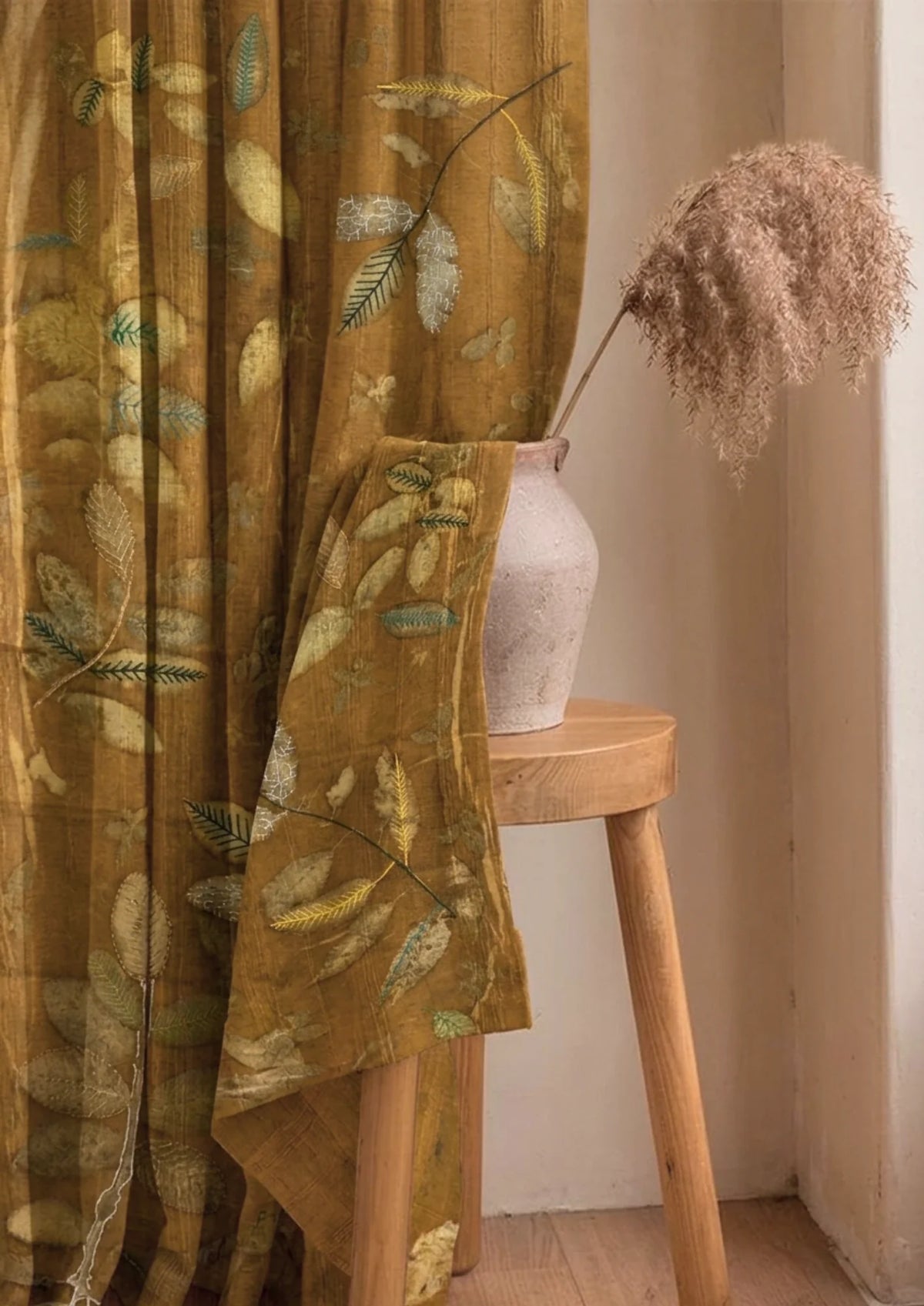 Brown Marigold dyed linen curtain with colorful embroidered leaves, handcrafted botanical home décor and sustainable window treatment curtain with a wooden stool and vase in a room setting