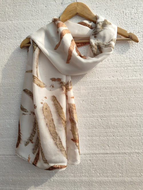 Neatly folded Ecoprinted Pure Silk Scarf on a wooden hanger against a light textured background