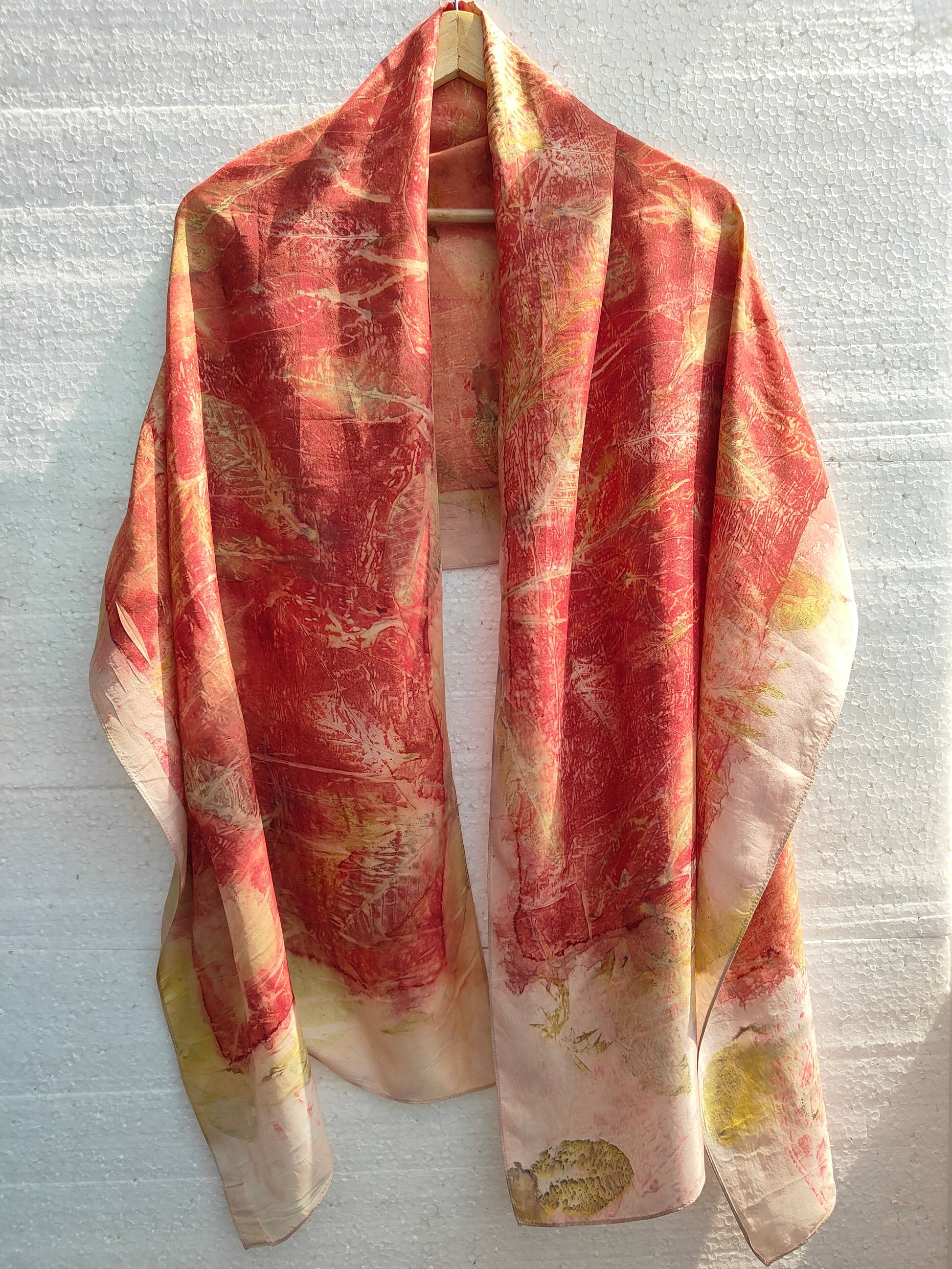 A hanging red colored ecoprinted scarf