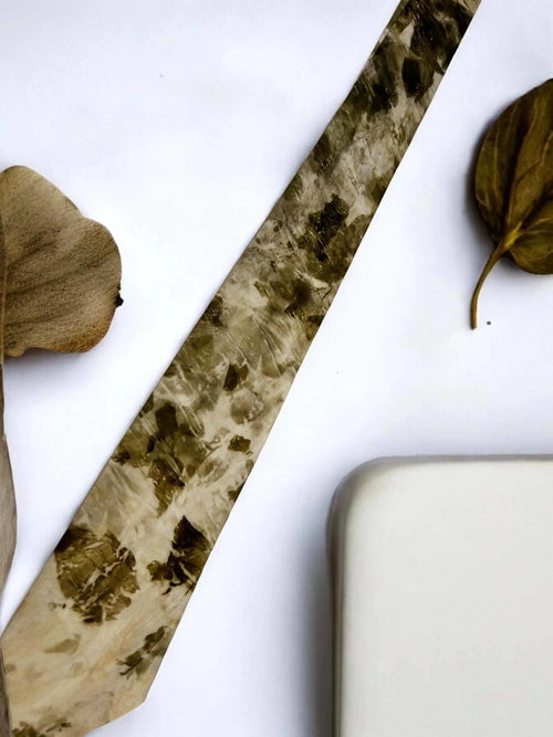 Decorative stone with leaf patterned silk tie on a white background