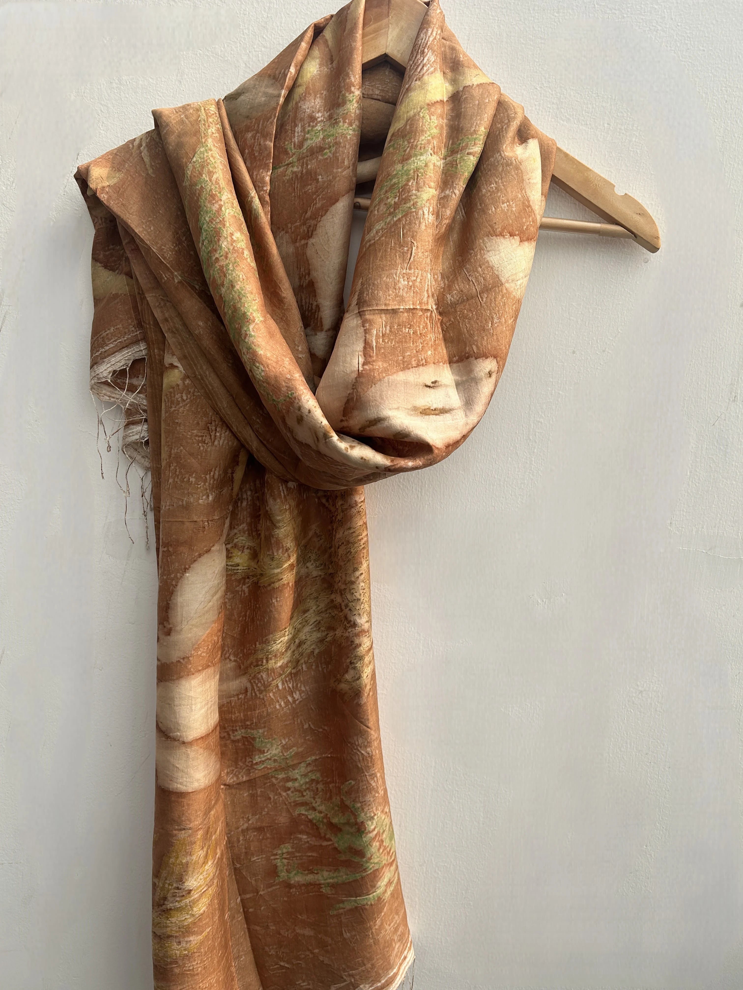 Brown and beige patterned Eco Printed Pure Silk Scarf on a wooden hanger against a light gray background