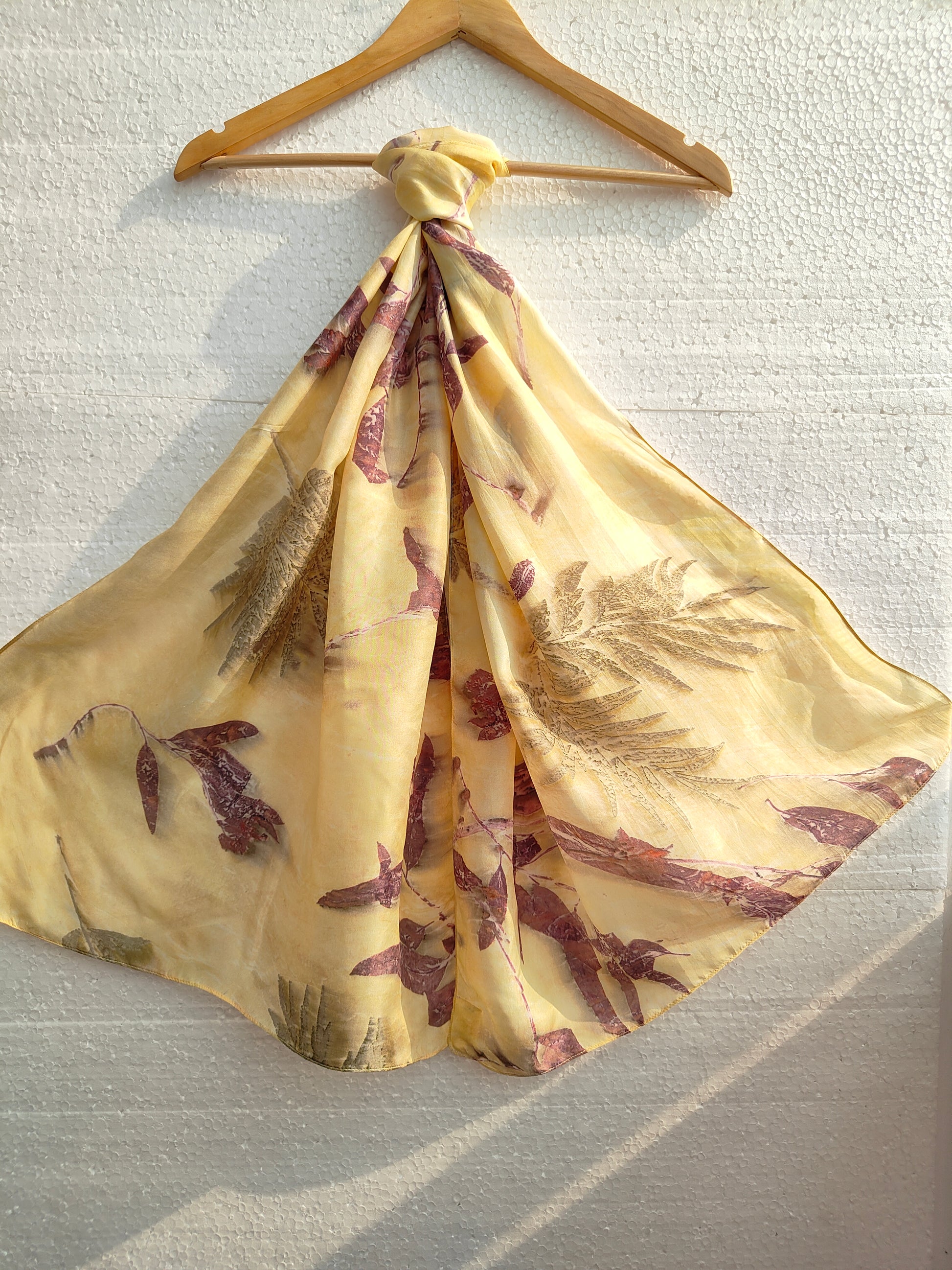 A hanging yellow scarf with ecoprinted leaves
