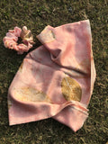 Pink ecoprinted silk scarf with  gold patterned leaves and scrunchie on grass