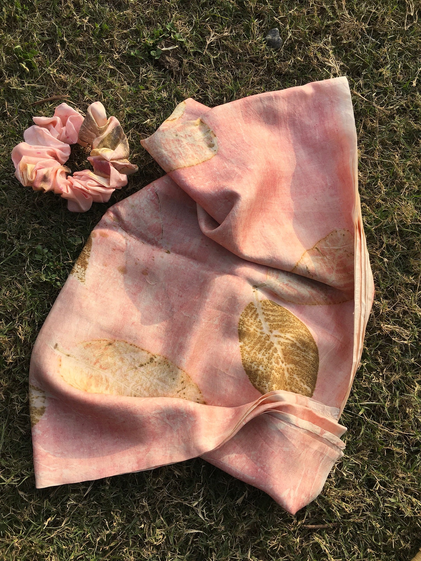 Pink ecoprinted silk scarf with  gold patterned leaves and scrunchie on grass