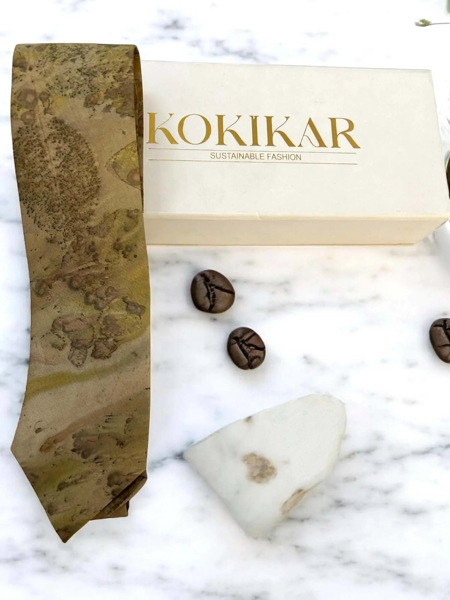 Kokikar sustainable fashion box with a patterned tie and stones on a marble surface