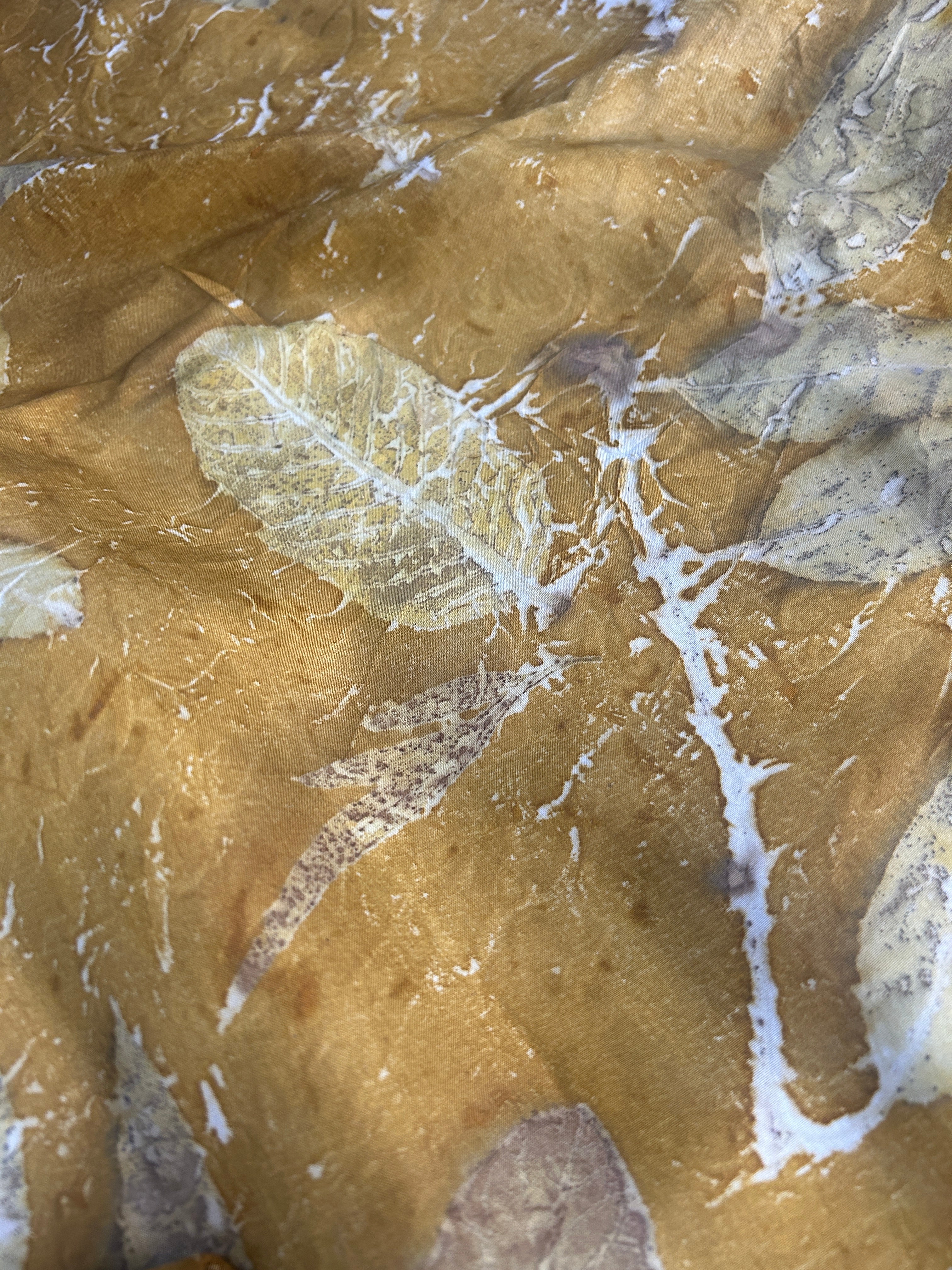 Yellow silk fabric with eco-printed leaf patterns.