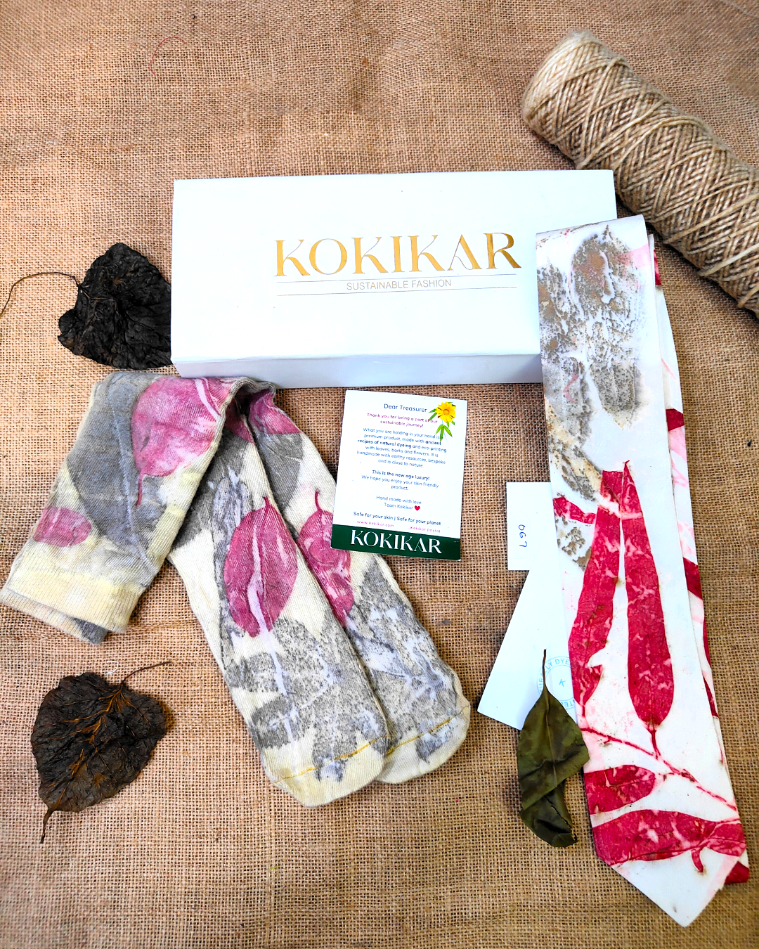 Two pairs of socks with leave patterns on a textured surface, featuring the Kokikar brand Heritage Ecoprinted Gift Hamper