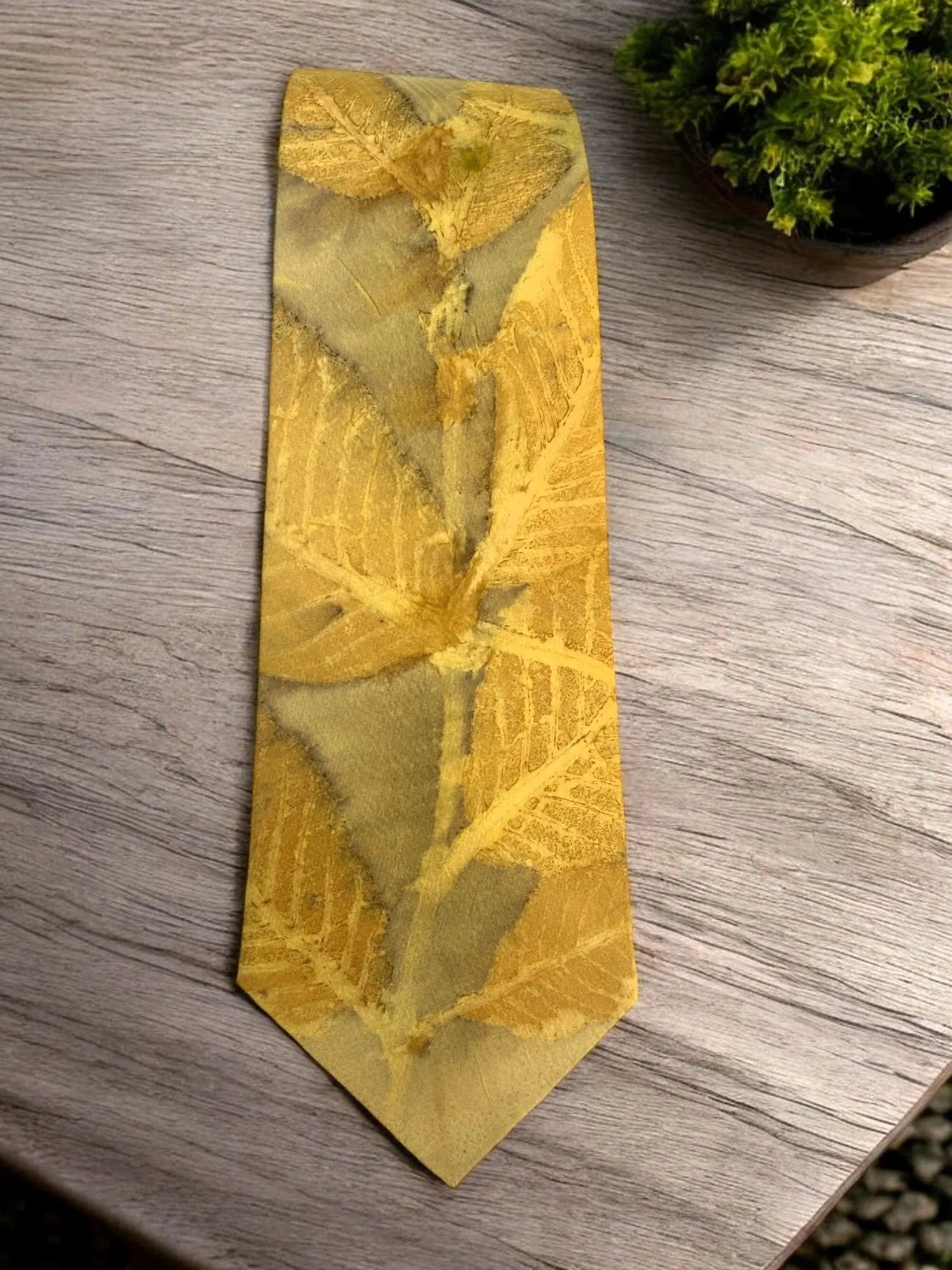 Gold tie with leaf pattern on a wooden surface