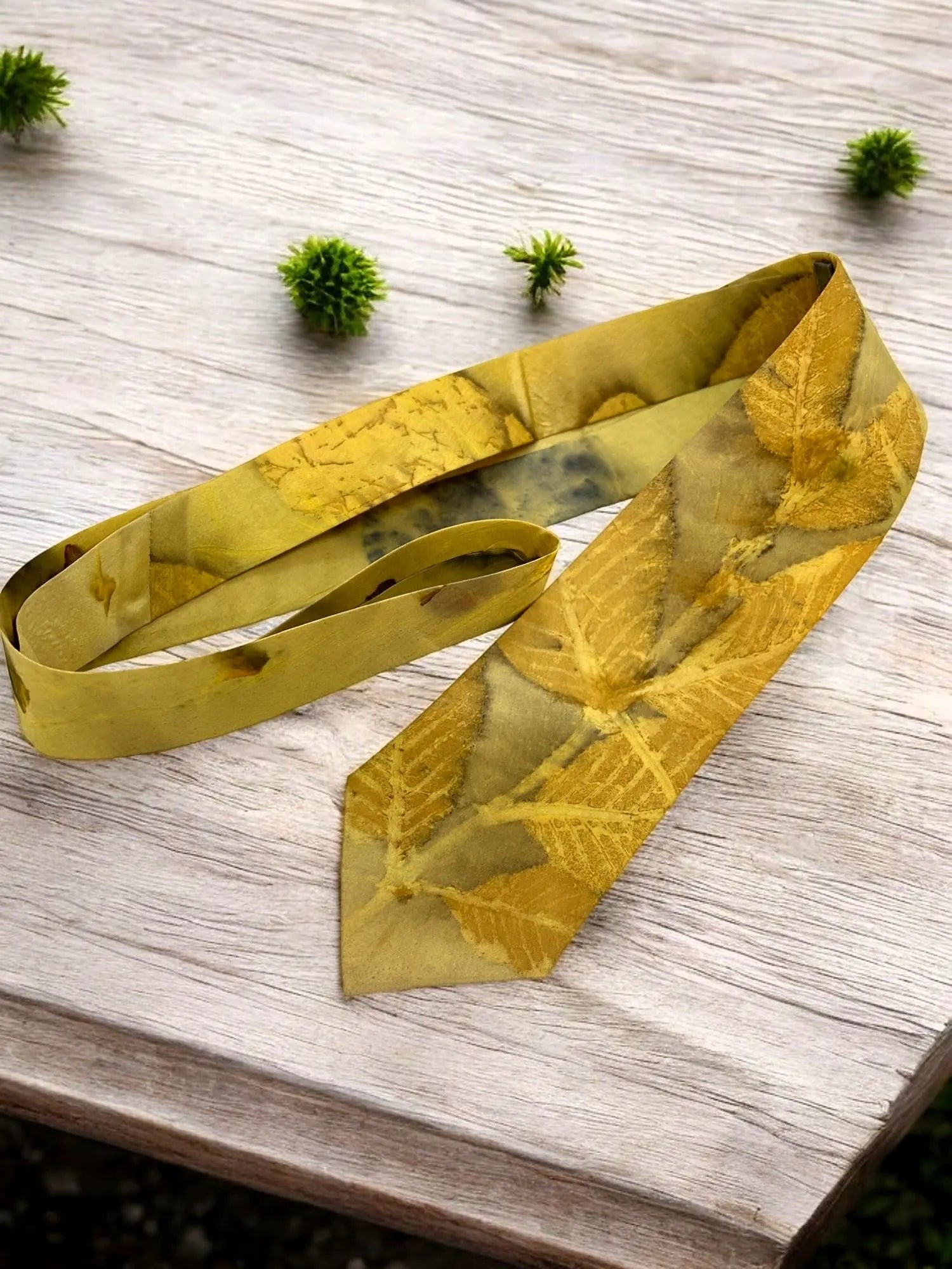 Yellow fabric silk tie with leaf pattern on a wooden surface