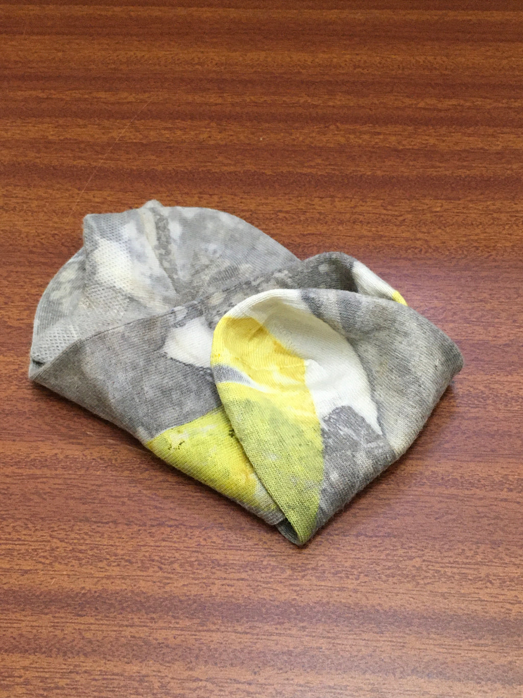 Folded gray, yellow, and white socks on a wooden surface