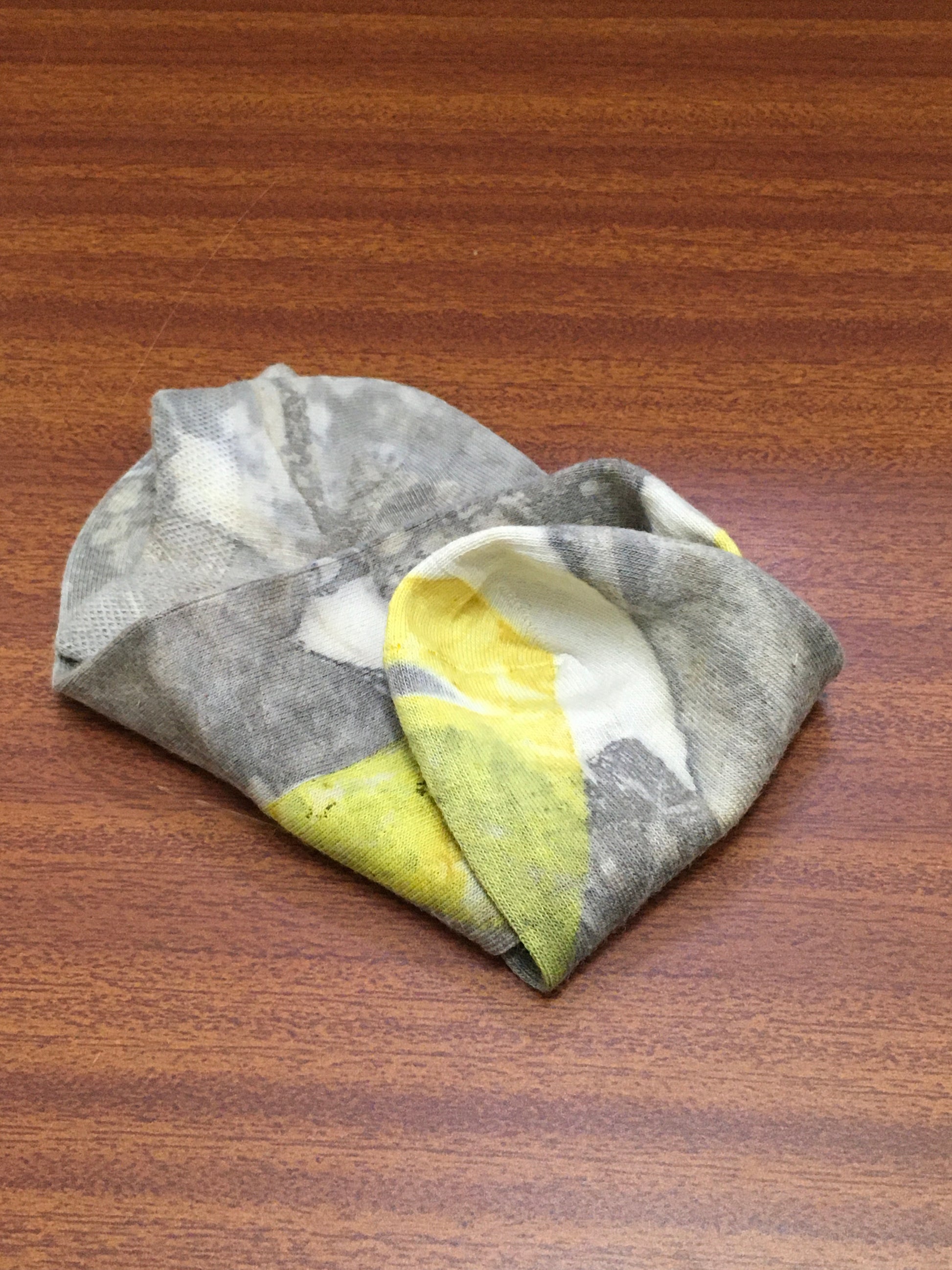 Folded gray, yellow, and white socks on a wooden surface