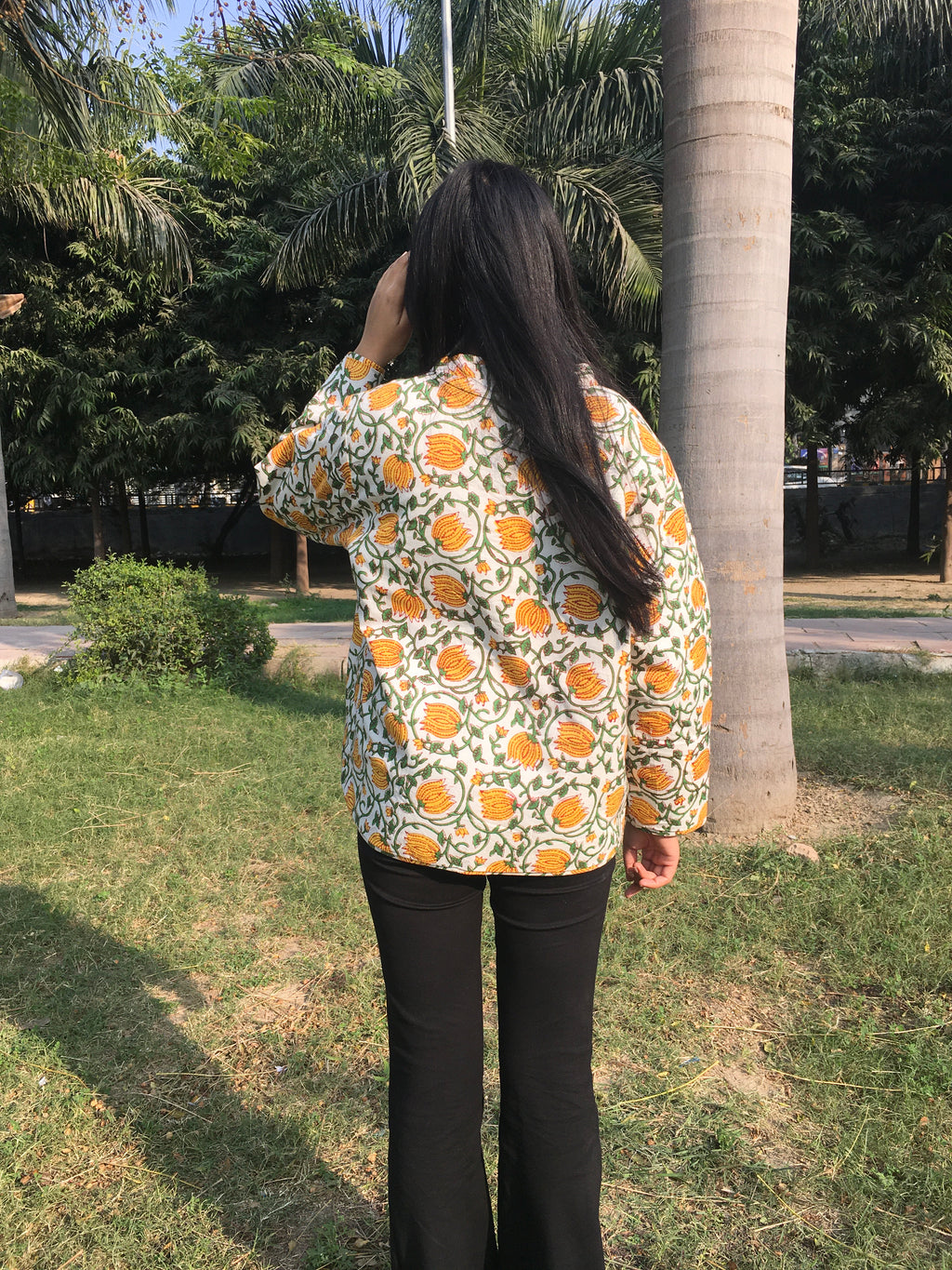 women wearing a floral-patterned reversible jacket in an outdoor setting with trees and grass.