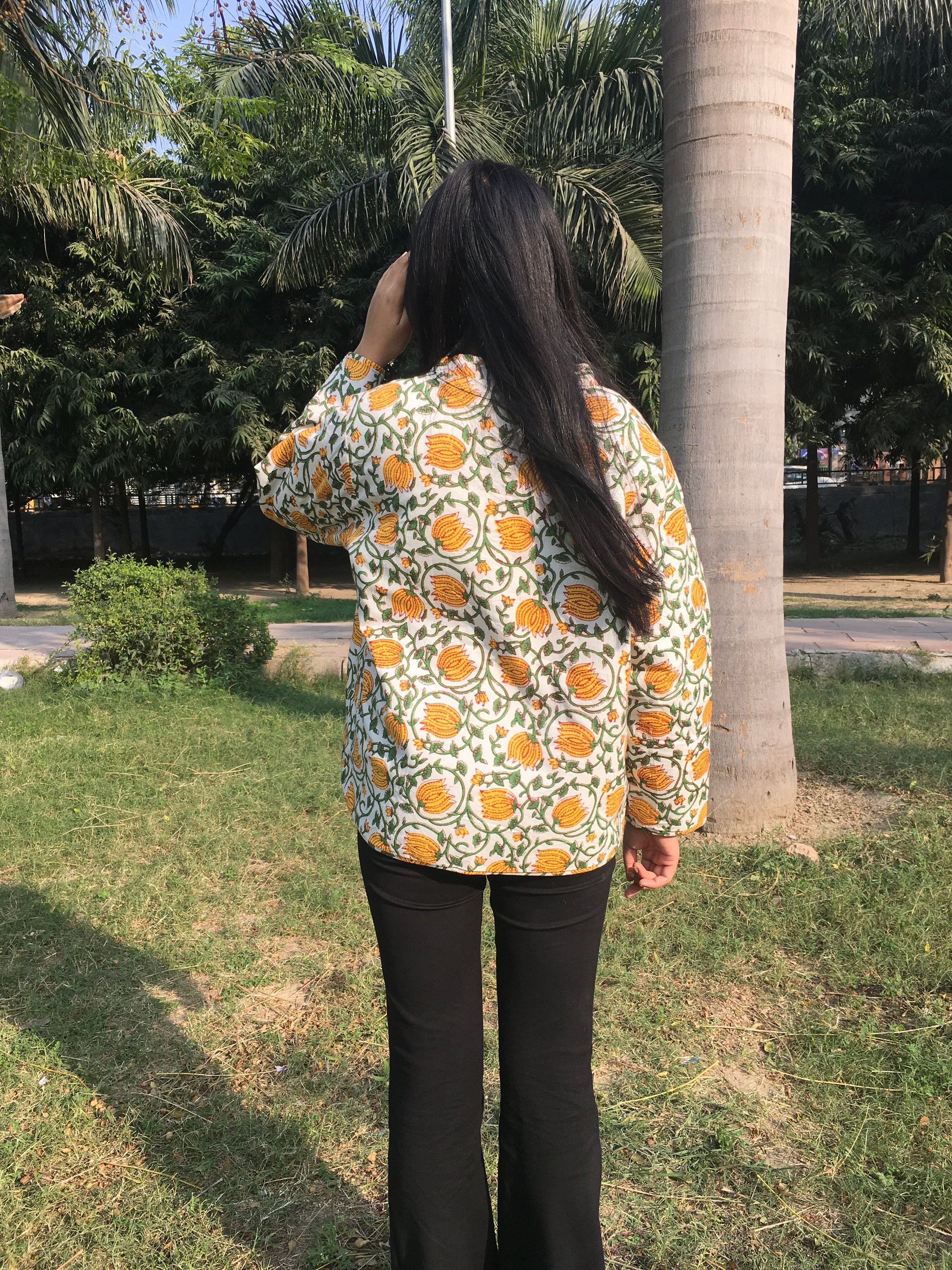 women wearing a floral-patterned reversible jacket in an outdoor setting with trees and grass.