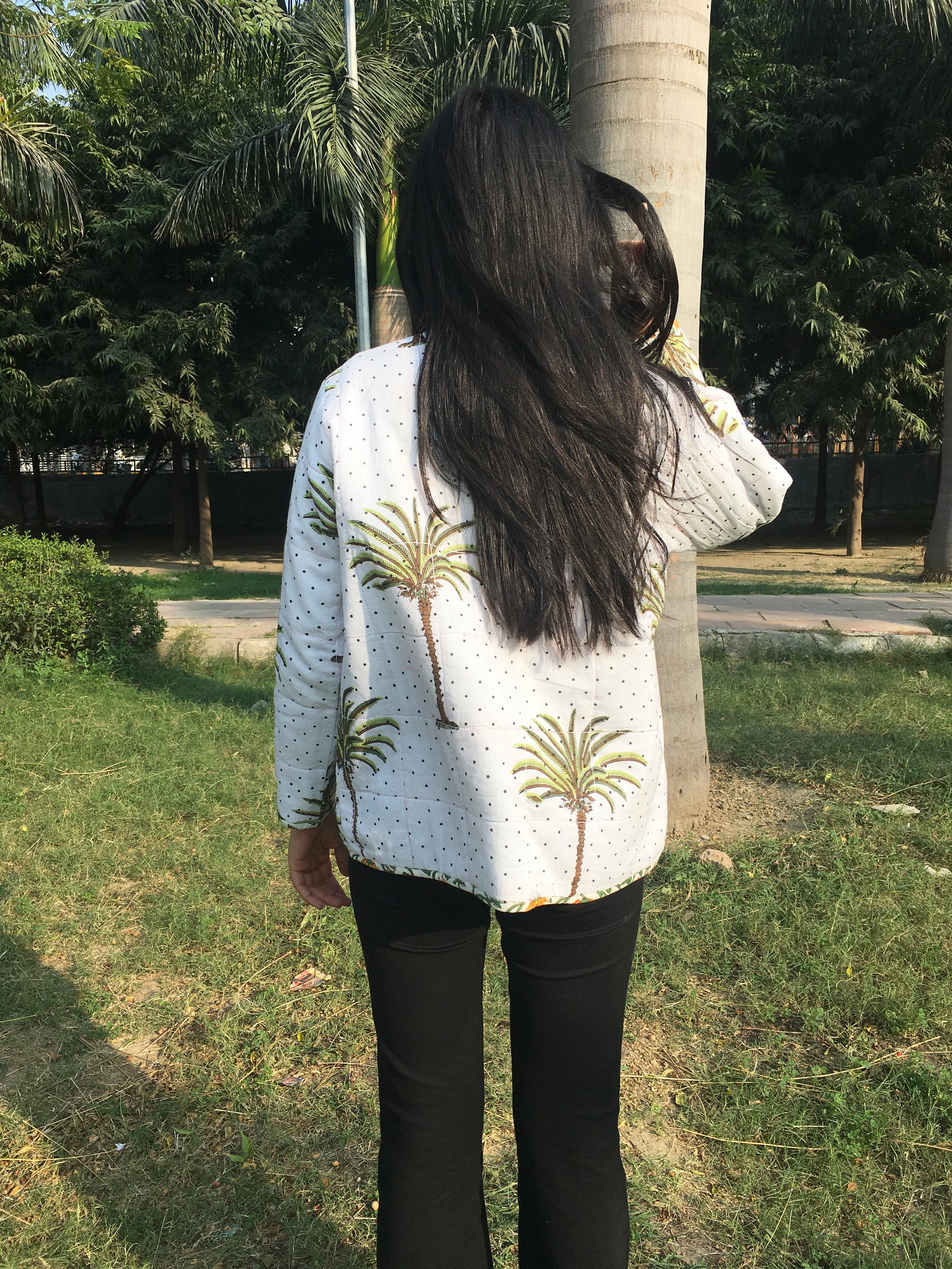 women wearing a patterned reversible jacket standing outdoors with trees and grass in the background