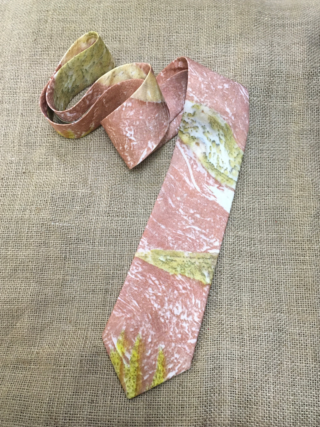 mens pure silk tie with pink and green pattern on a textured beige background