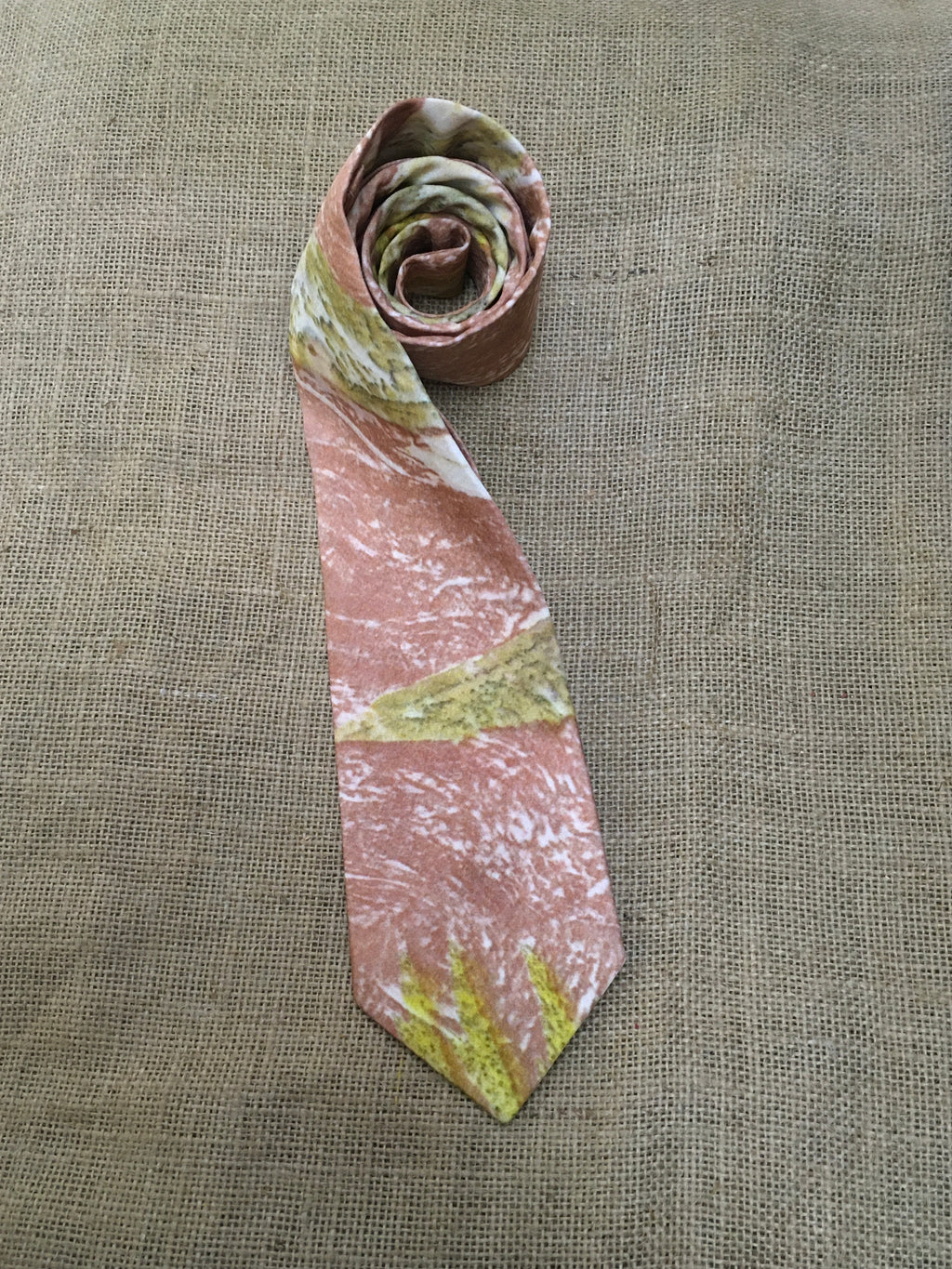 Marbled pink and green mens silk tie on a textured beige background