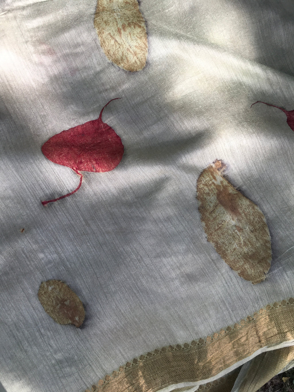 Close-up of Ecoprinted Matka Silk Saree with embroidered leaves on a light background