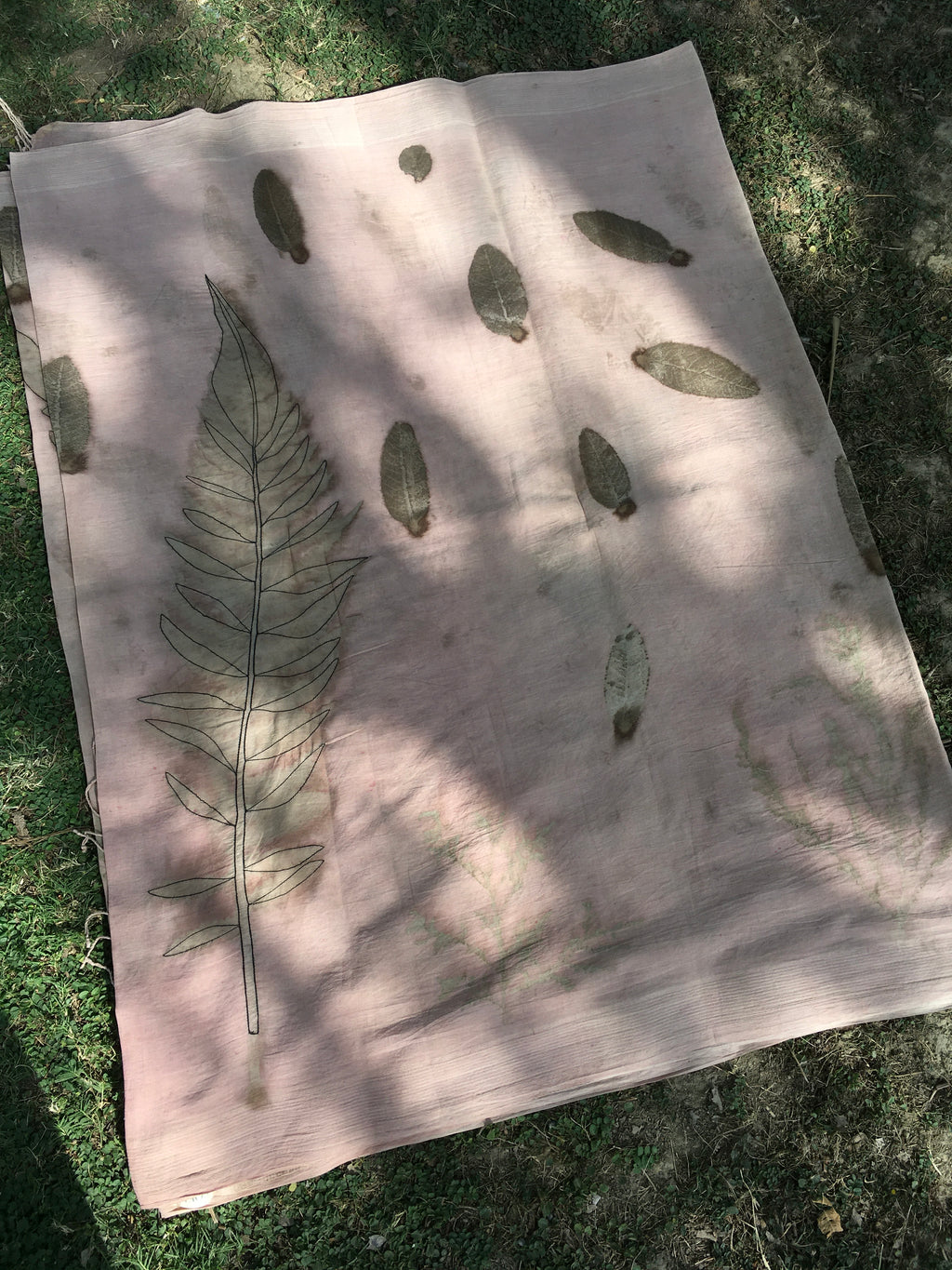 ecoprinted cotton saree with pressed leaves on a grassy background