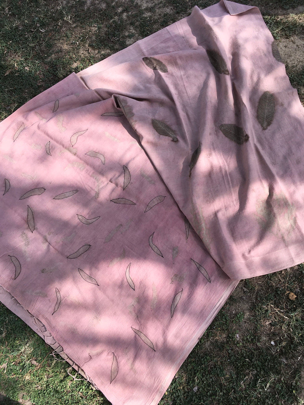 Pink ecoprinted cotton saree with leaf patterns on a grassy surface