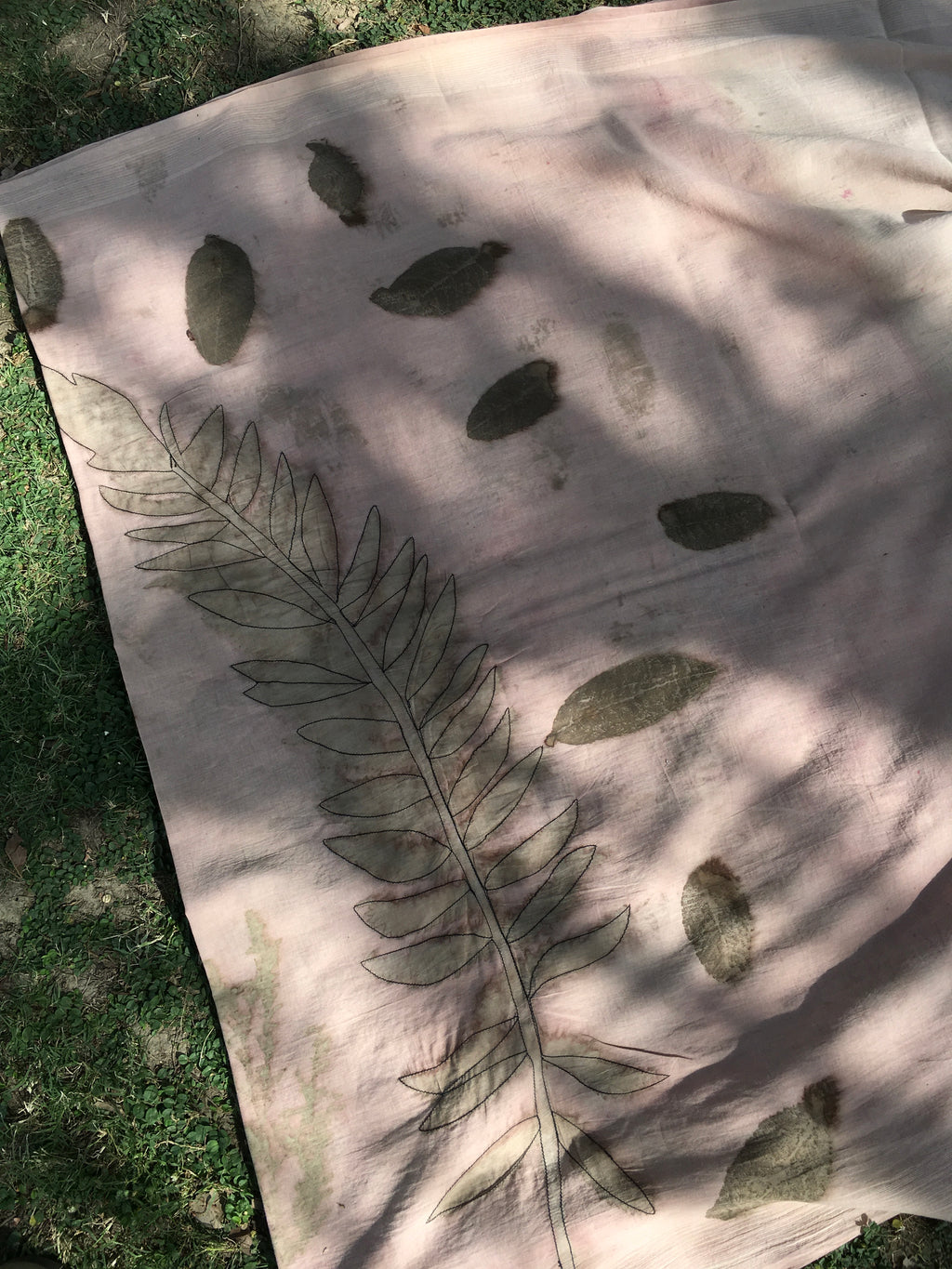ecoprinted cotton saree with leaf patterns on a grassy background