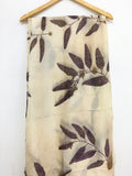 Logwood Eucalyptus Eco Printed Pure Silk Scarf with leaf pattern hanging on a wooden hanger against a white background