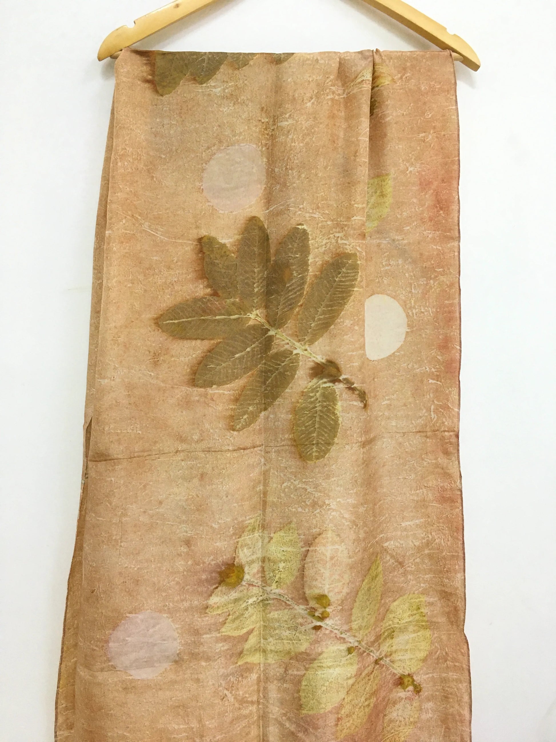 Handcrafted pure silk scarf featuring eco-printed guava leaves surrounding a moon-inspired white circular design, created using natural dyes and sustainable botanical printing techniques.