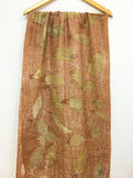 Brown pure silk scarf with green leaf pattern hanging on a wooden rod against a white background