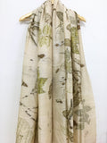 Botanical Eco Printed Pure Silk Scarf with nature-themed design draped over a wooden hanger on a white background