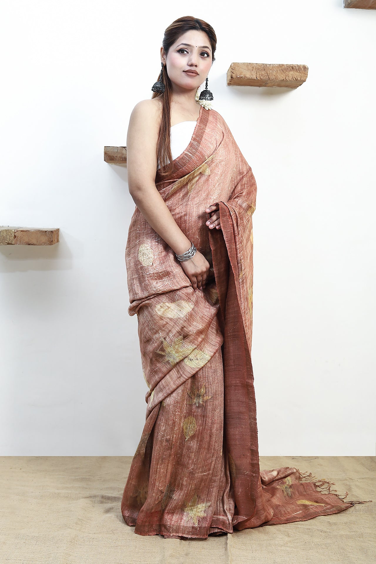 Woman wearing a pure matka silk saree against a white wall.