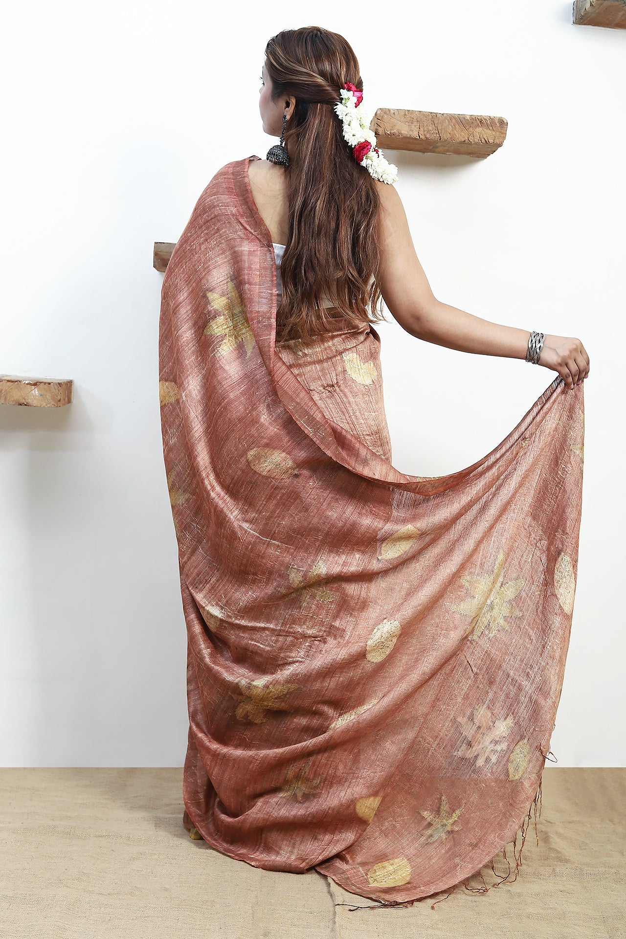 Woman wearing a pure matka silk saree, standing against a white wall.