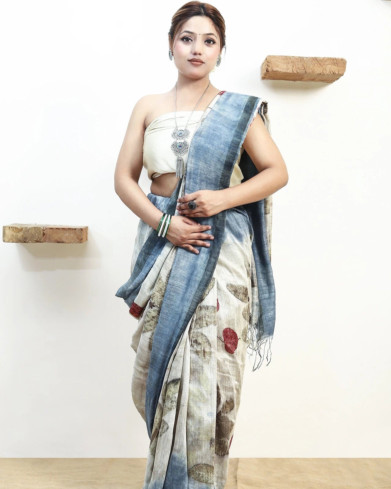 Woman wearing a pure matka silk saree with an ecoprinted saree against a white wall.