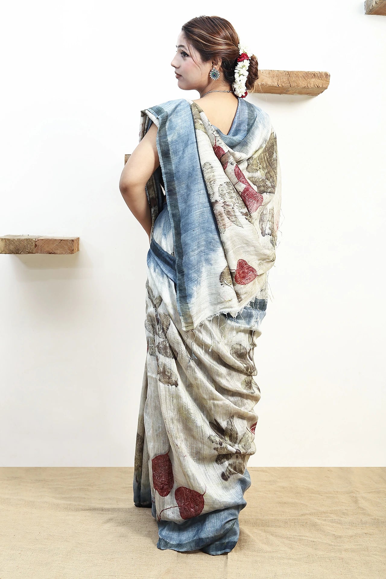 Woman wearing a pure matka silk ecoprinted saree with a scenic design in a minimal indoor setting