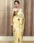 Woman wearing a yellow ecoprinted saree with a wooden panel background