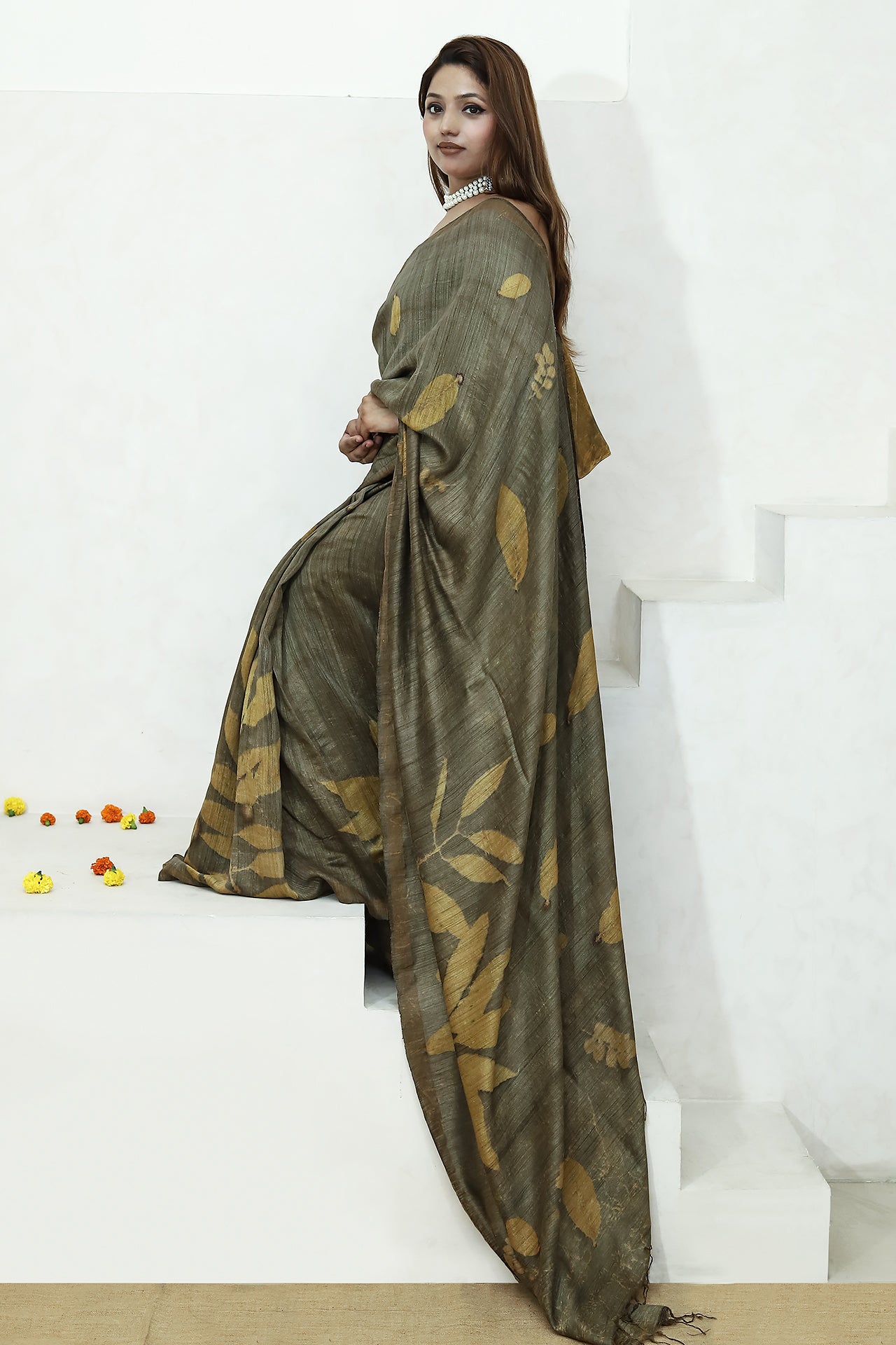 Woman wearing a long, dark green ecoprinted saree on a white background