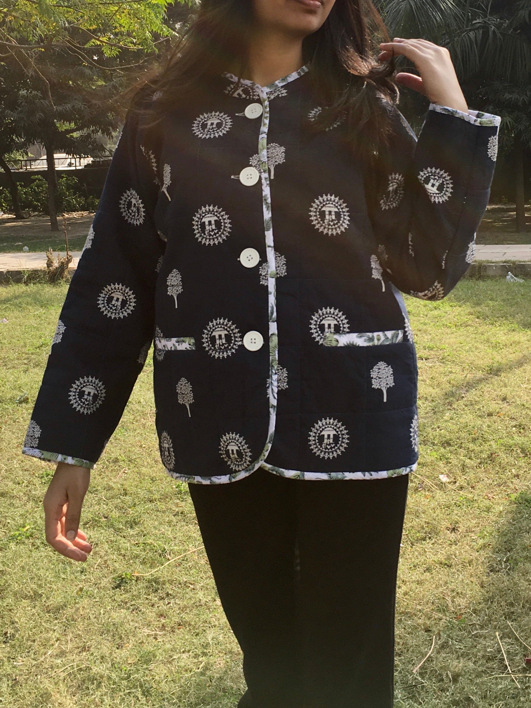 Person wearing a blue double sided reversible jacket outdoors on a grassy area