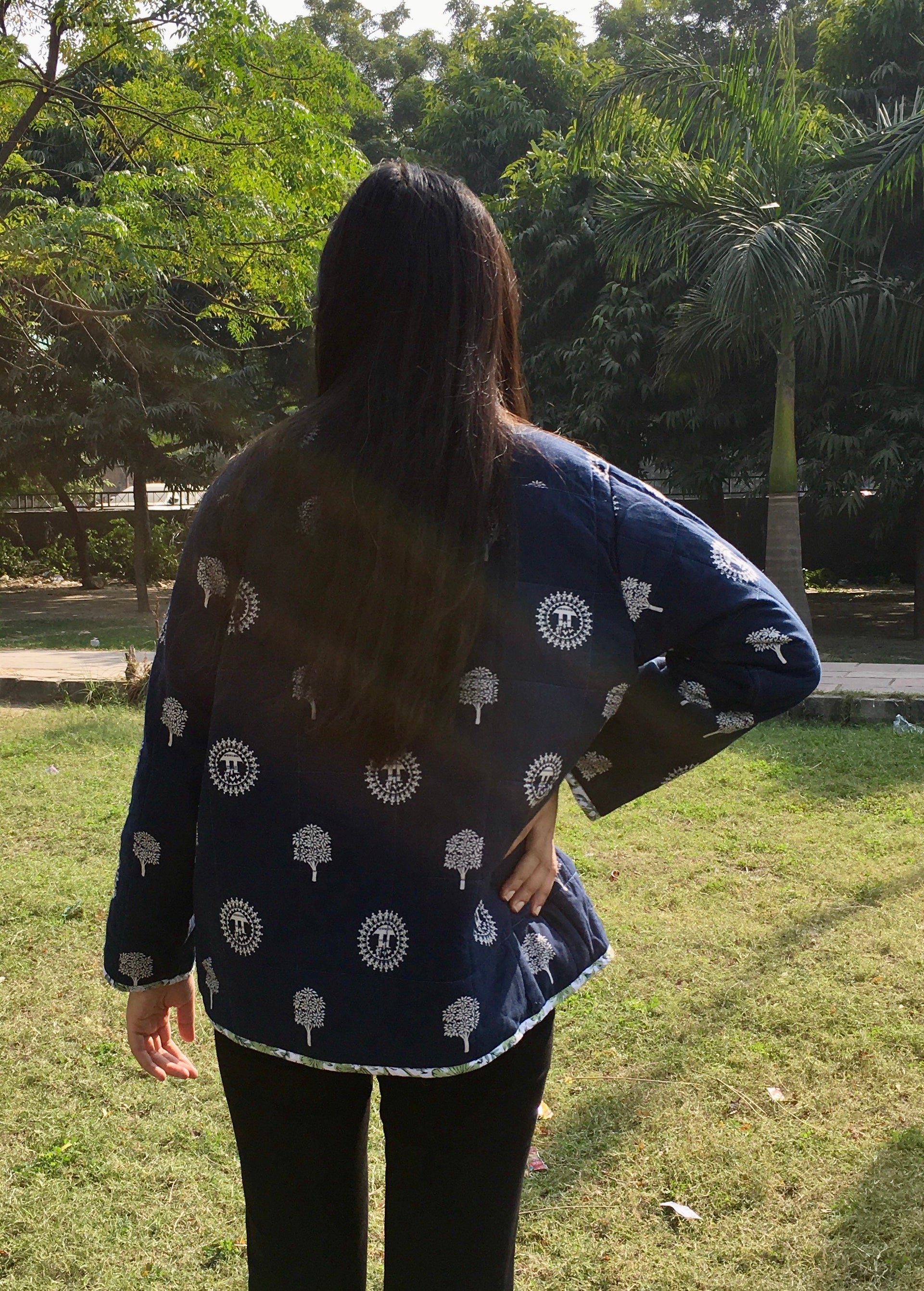 Person wearing a navy blue patterned reversible jacket in a park setting