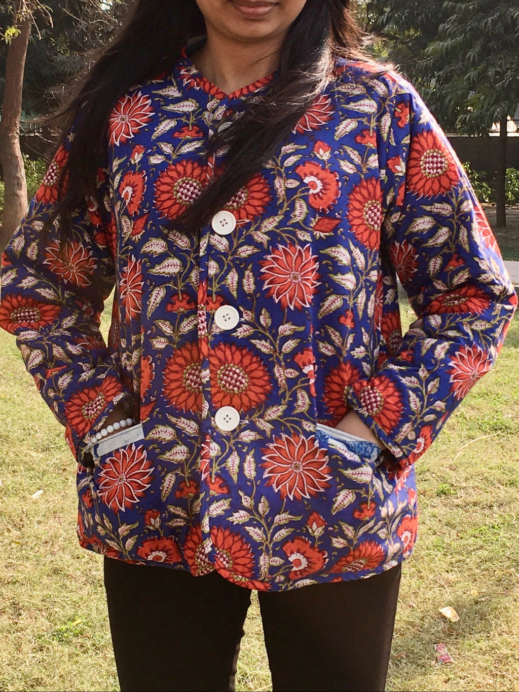 Woman wearing a colorful floral reversible jacket outdoors in a park