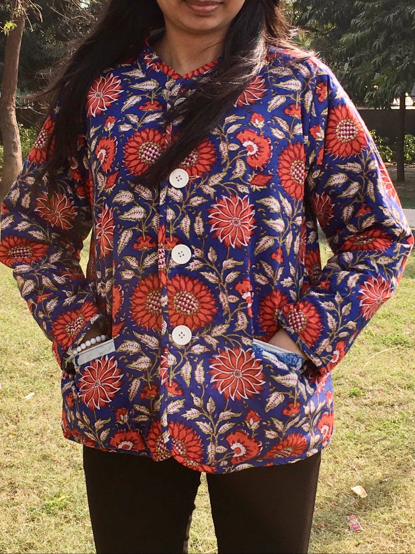 Woman wearing a colorful floral reversible jacket outdoors in a park