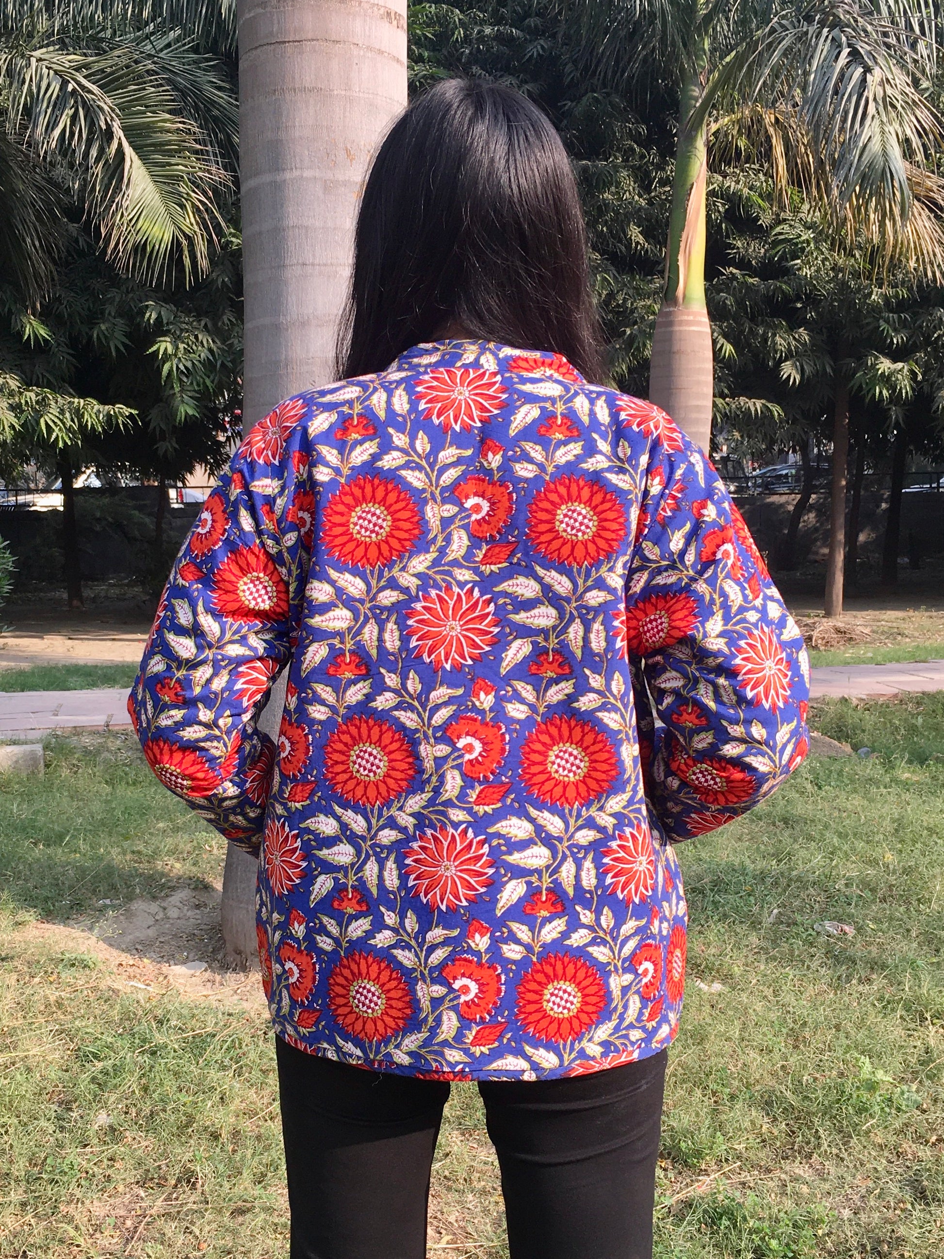Person wearing a colorful floral reversible jacket in an outdoor setting