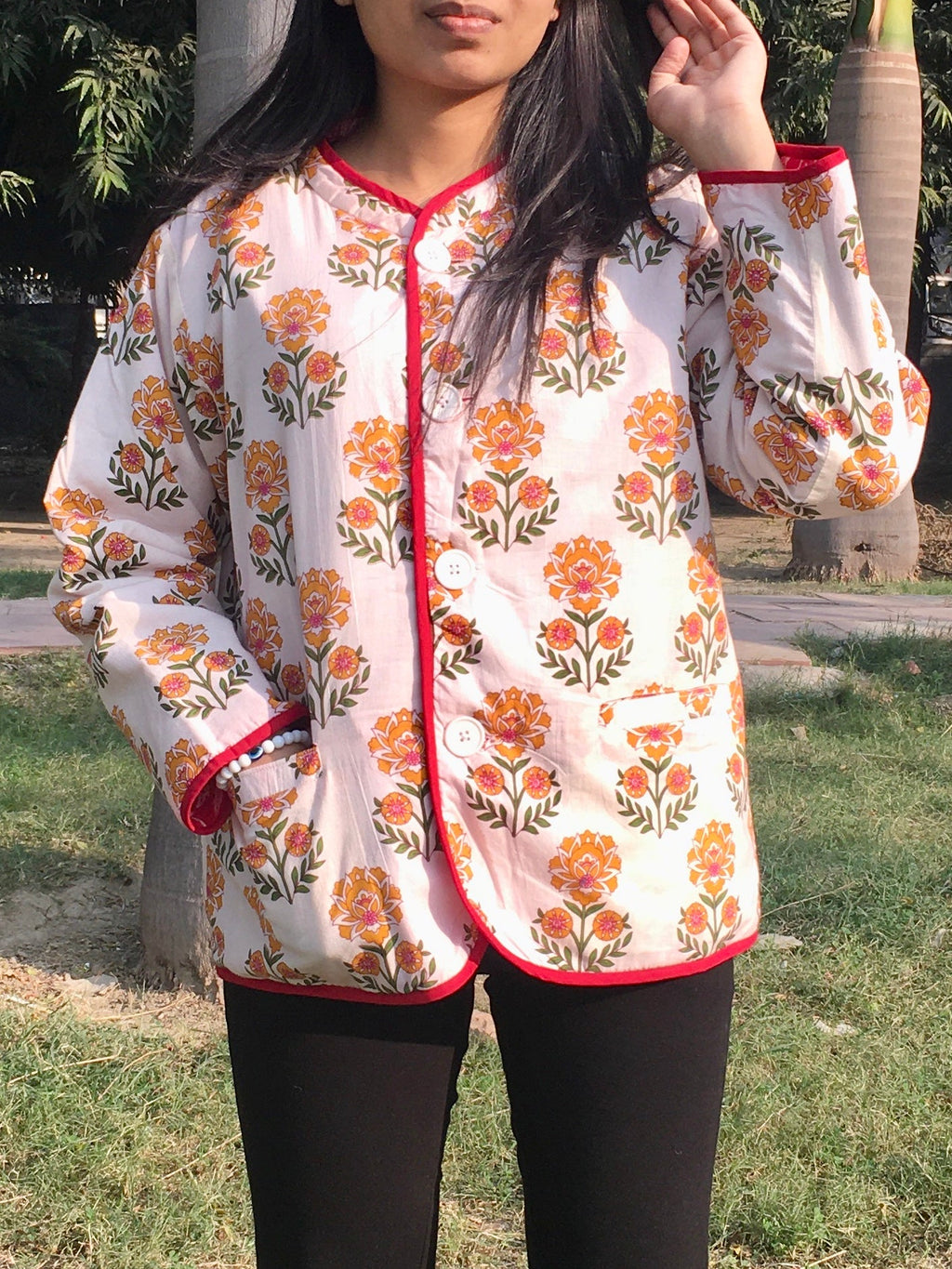 Woman wearing a floral reversible jacket outdoors with trees in the background