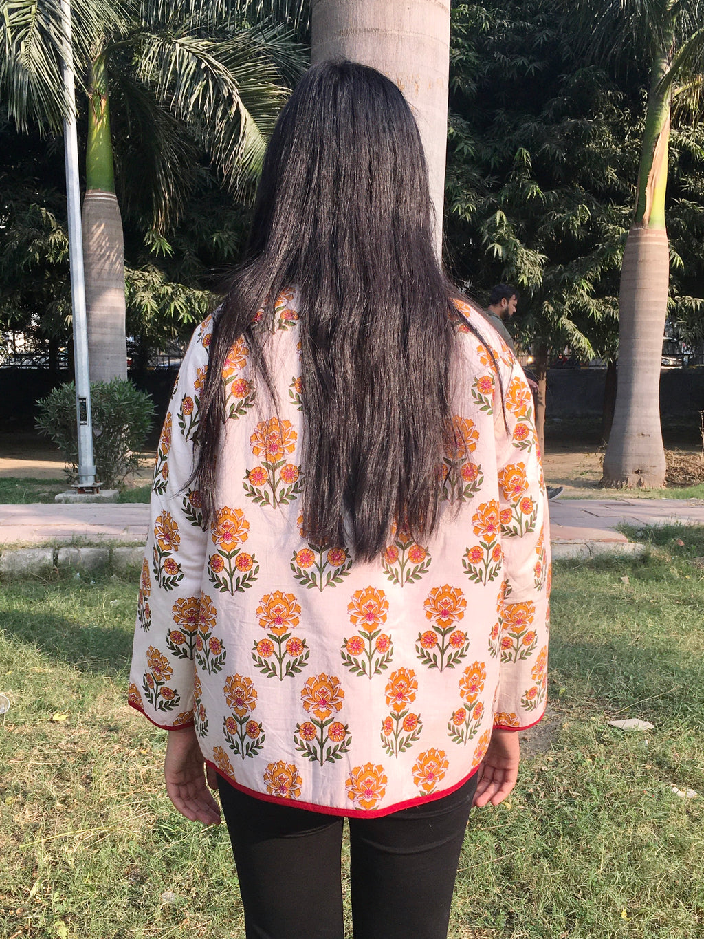 women wearing a floral patterned reversible jacket outdoors with trees in the background