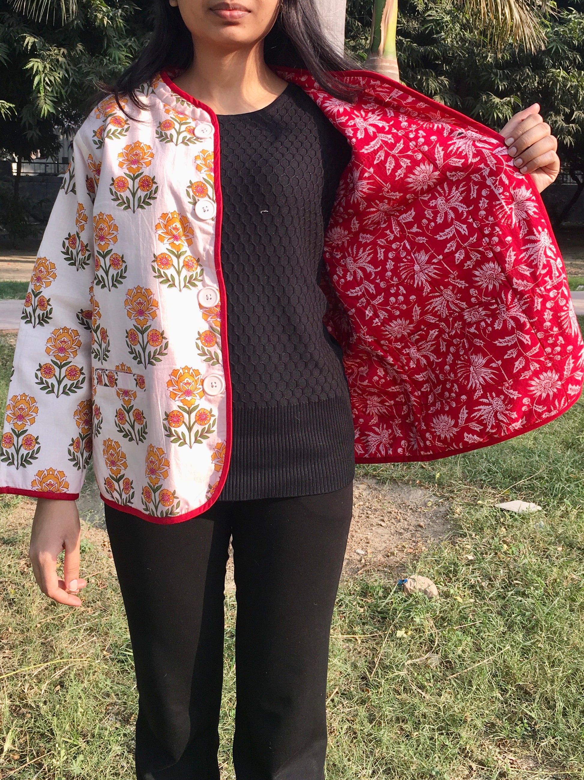 women holding a red and white patterned reversible jacket outdoors