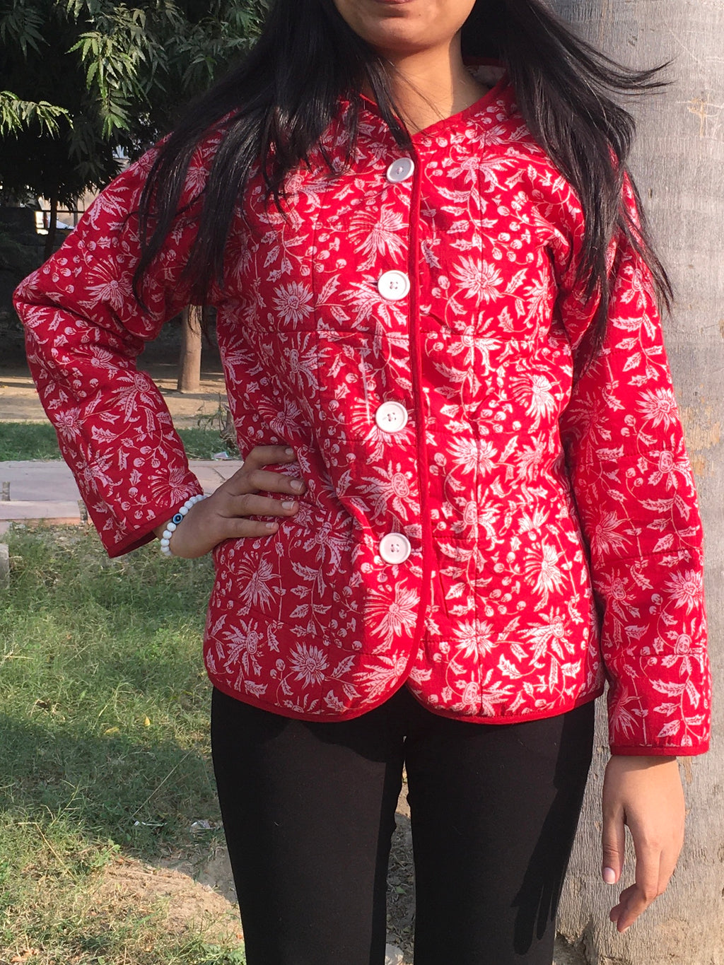 women wearing a red floral patterned reversible jacket outdoors.