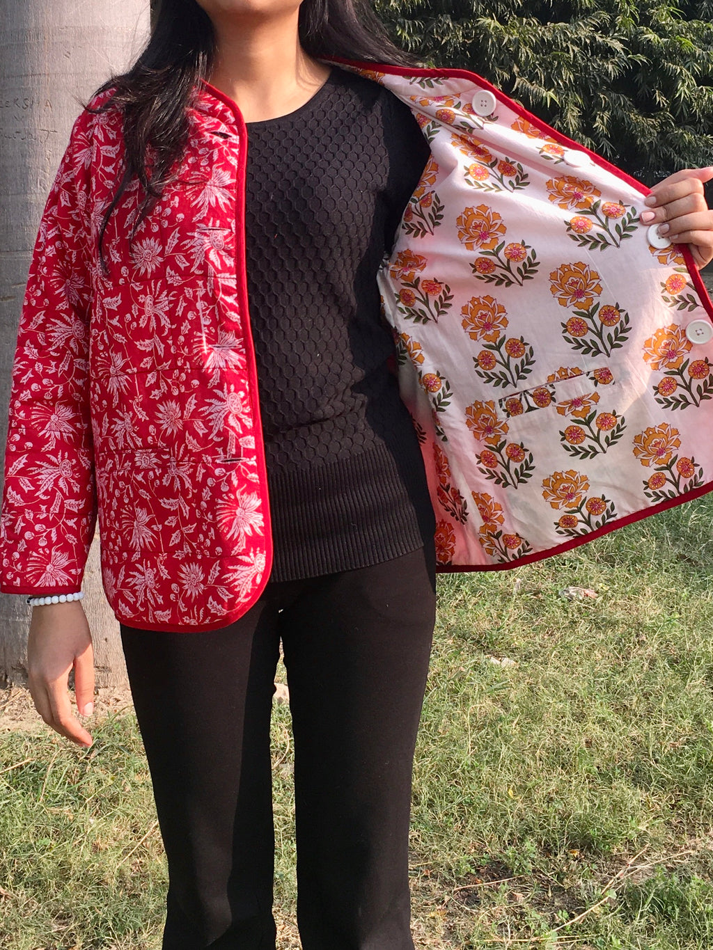 women holding a floral-patterned reversible jacket outdoors