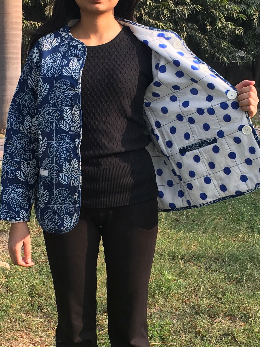 women holding a blue and white patterned reversible jacket outdoors