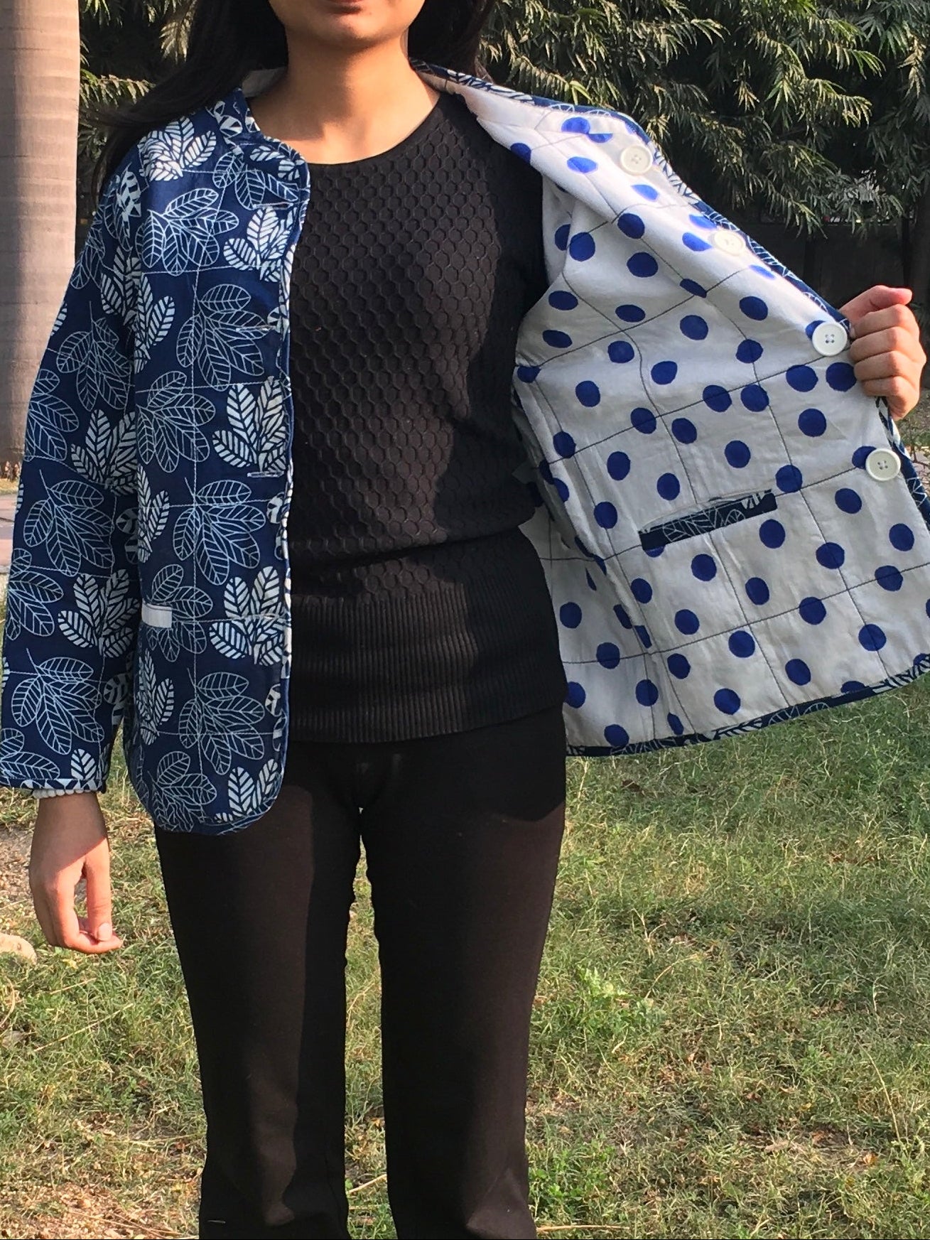 women holding a blue and white patterned reversible jacket outdoors