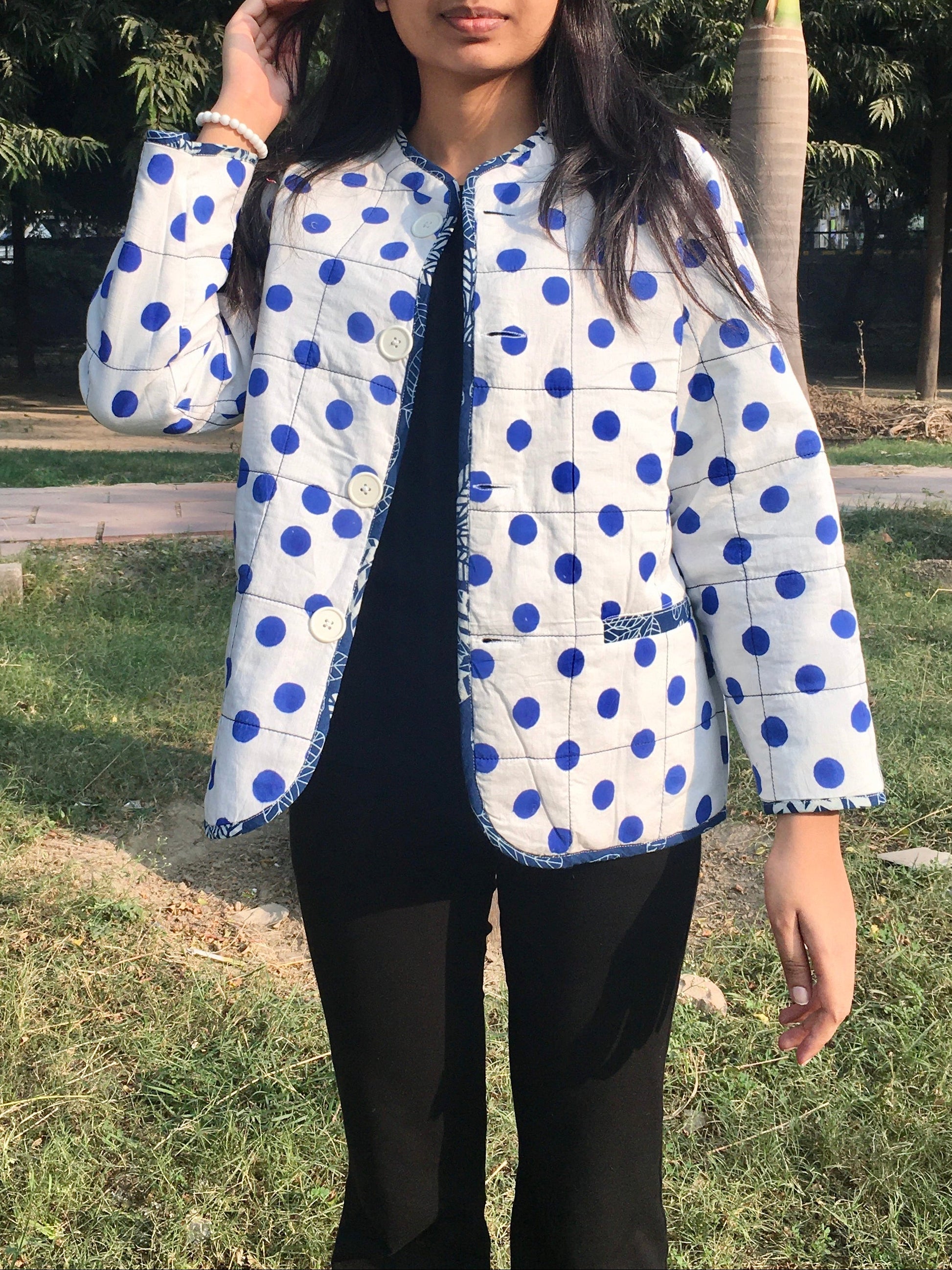 women wearing a white reversible  jacket with blue polka dots outdoors