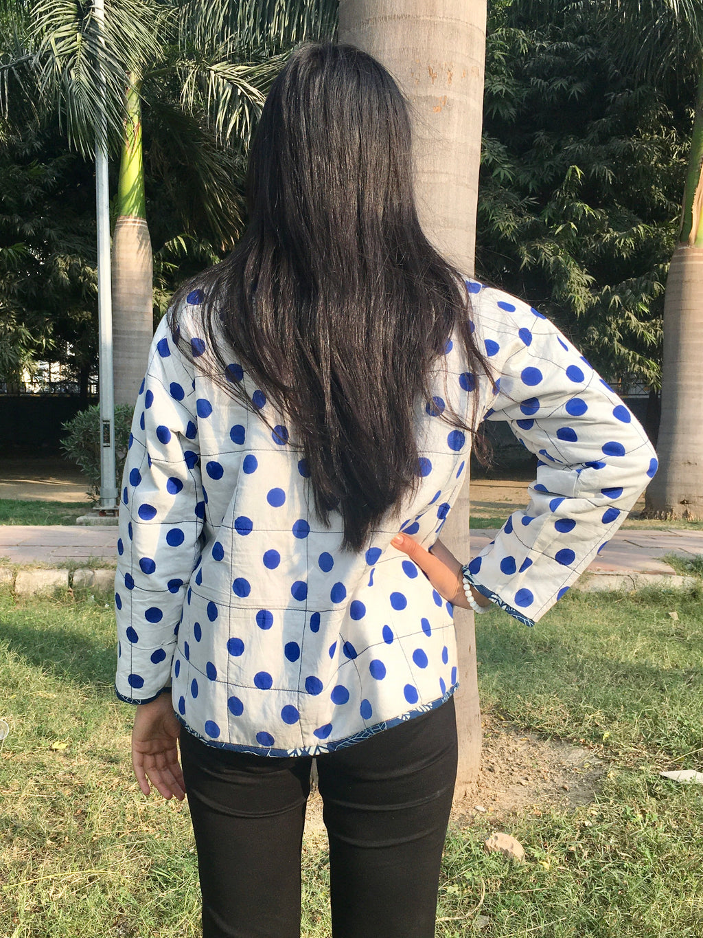 women wearing a white shirt with blue polka dots reversible jacket in an outdoor setting