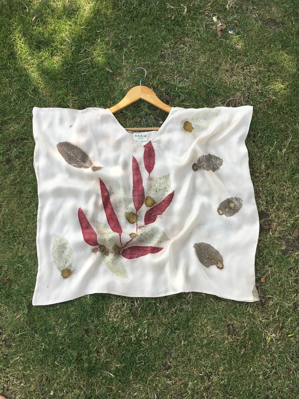 White Kaftan Flared Top with red and green leaf patterns on a grassy background