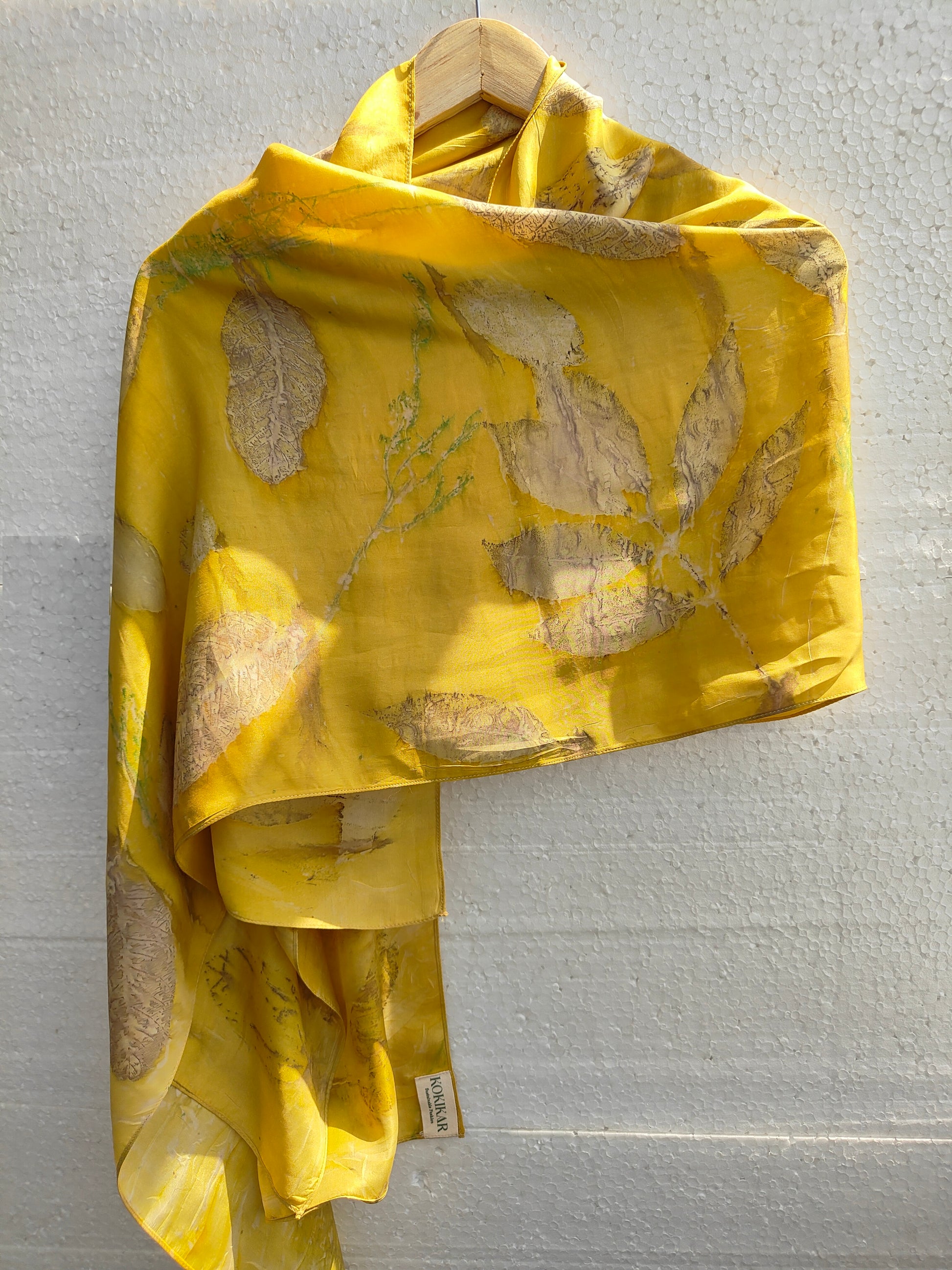 A yellow scarf hanging with ecoprinted jamun leaves